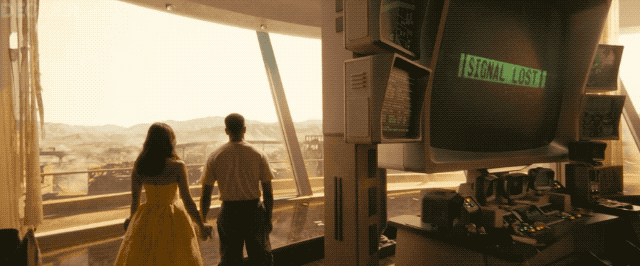 Люси и Максимус держатся за руки, пока лицо Роберта Хауса глючит на экране